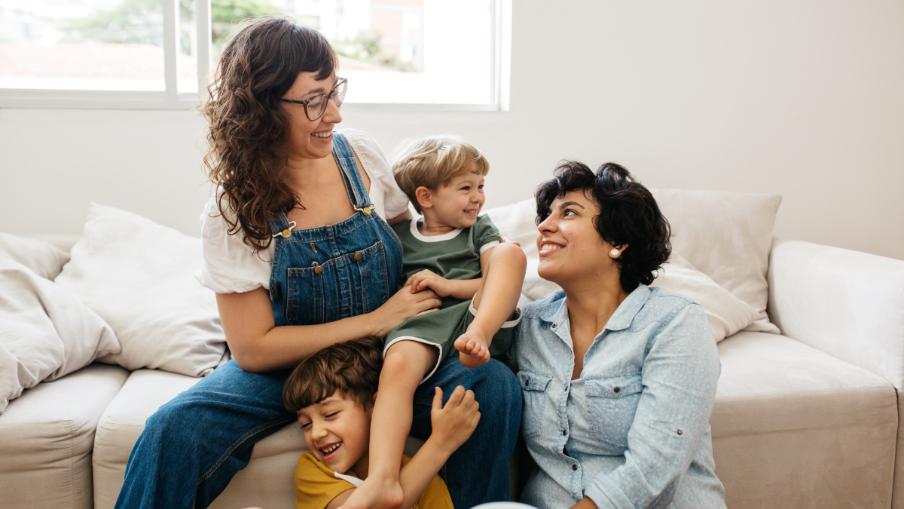 
		zwei Frauen und zwei Kinder sitzen auf einem Bett
	