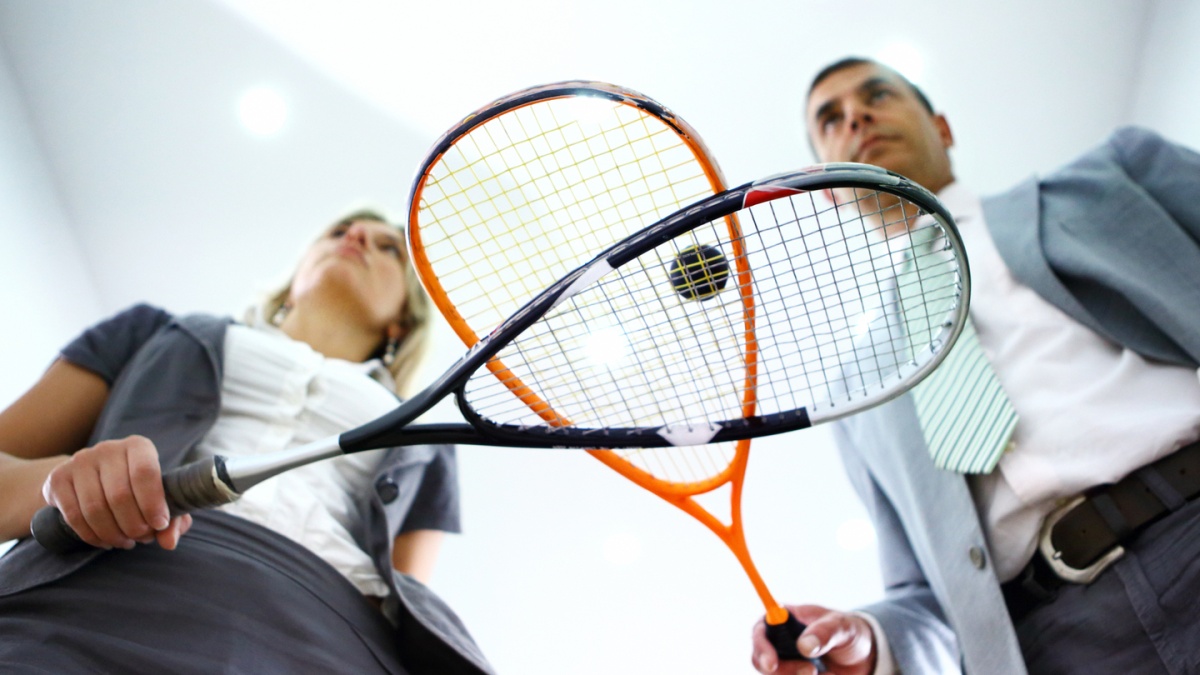 man sieht Menschen im Büro-Outfit, die Squash spielen