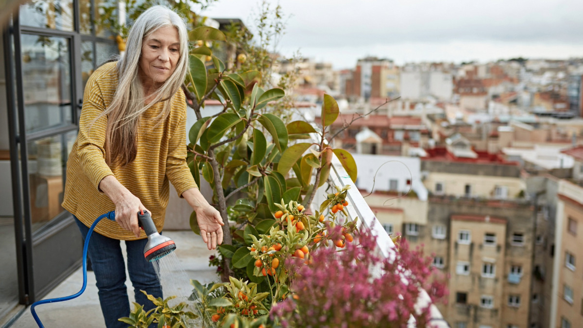 eine Frau giesst auf einem Dachgarten