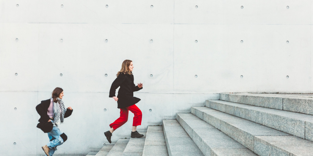 Zwei Frauen rennen die Treppe hintereinander hoch