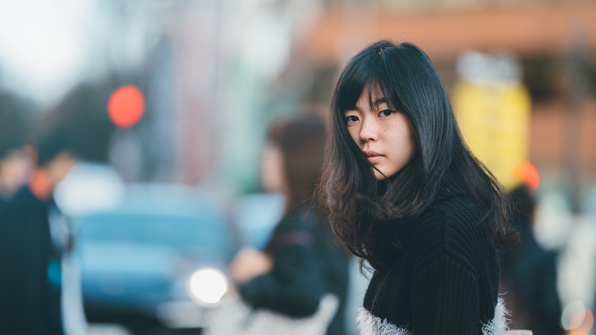 Eine junge asiatische Frau auf der Straße schaut sorgenvoll in die Kamera